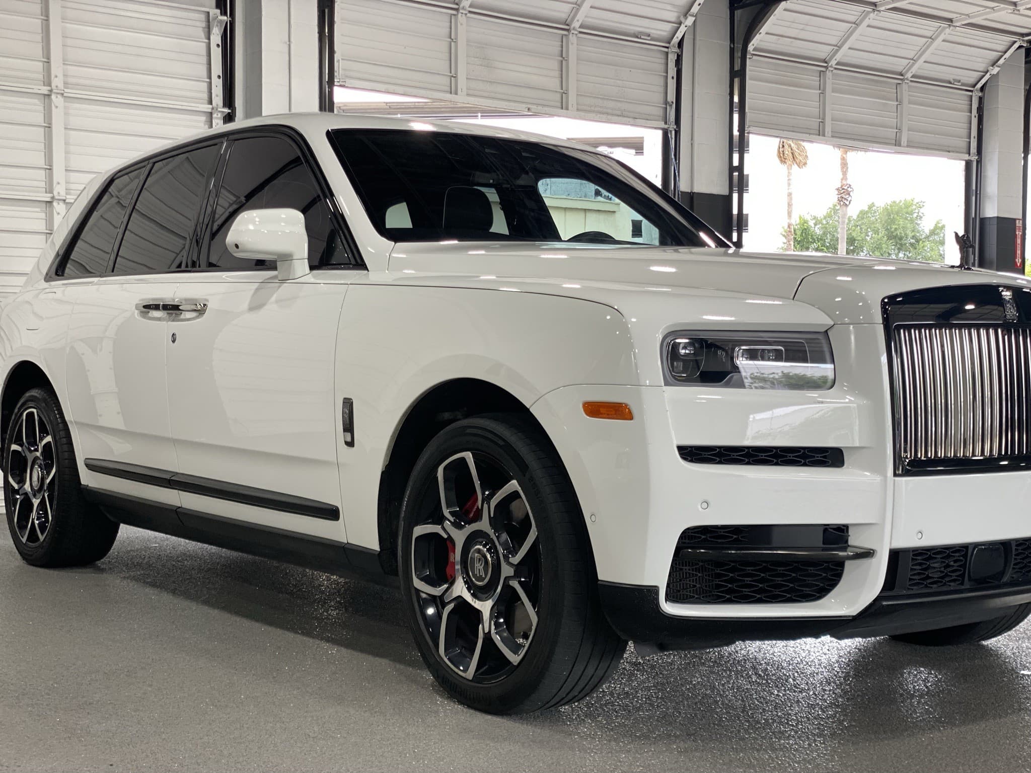Rolls-Royce Cullinan Black Badge in white, three-quarter front exterior with palm trees
